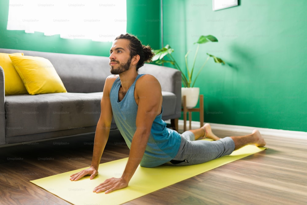 Smiling young man practicing a cobra pose. Attractive man exercising with yoga and feeling relaxed