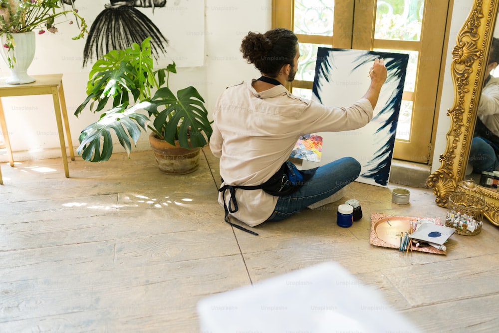 Sentir-se inspirado. Jovem pintor hispânico praticando a técnica de pintura a óleo em uma tela em branco