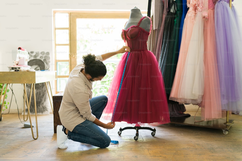 Créateur de mode tendance mesurant le tissu tout en concevant une nouvelle belle robe pour un client