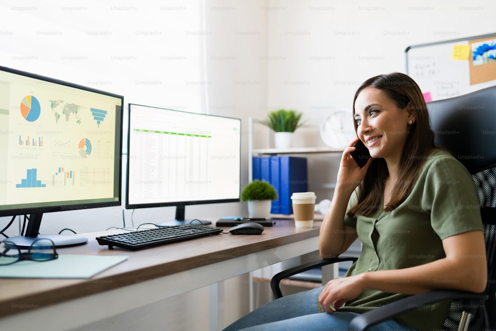 Cheerful business administrator talking on the phone with a client and making a sales deal. Latin young woman working from home as a freelancer