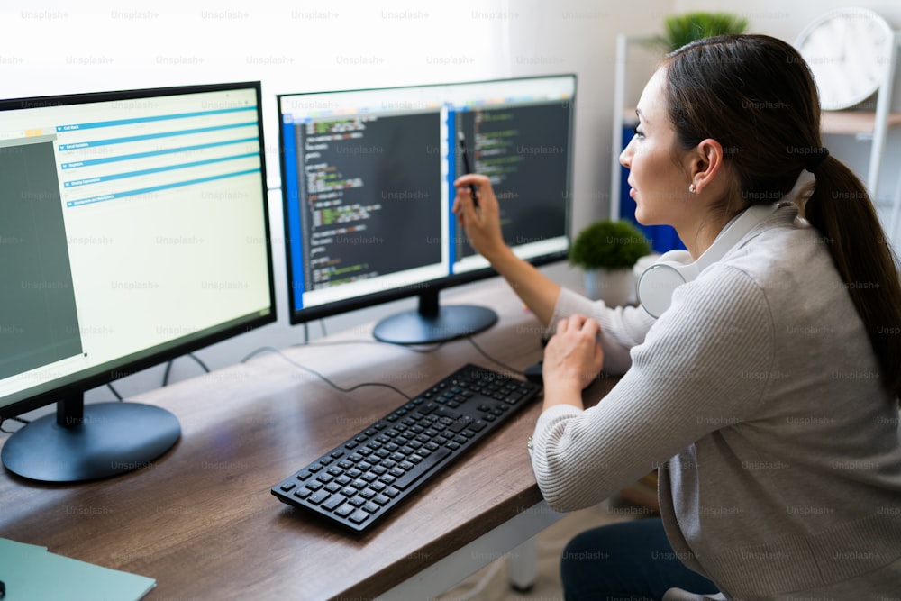 Attractive woman working on programming software app. Young woman coding and checking her work on the computer