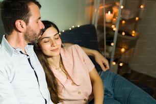 Fidanzato amorevole che bacia la sua ragazza sulla fronte mentre trascorre un po 'di tempo insieme durante un appuntamento casuale a casa