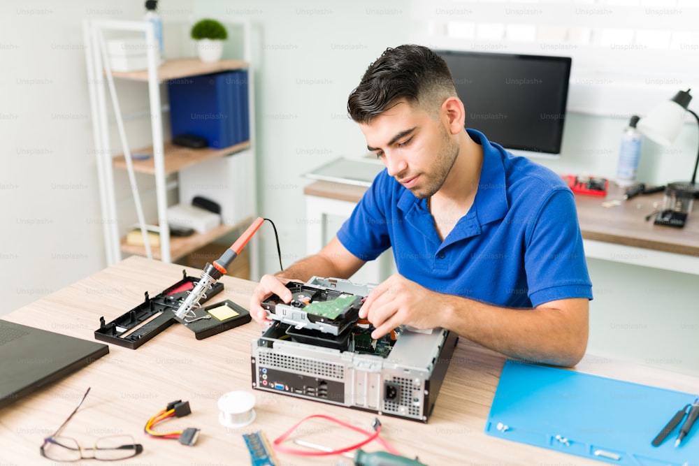 Young man finding out if the connection works. Hispanic technician connecting a new hard drive on a computer and checking the hardware