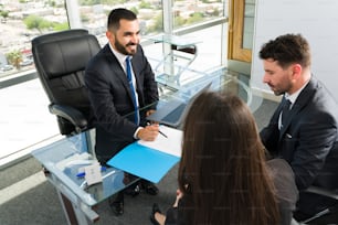 Giving good legal information. Company executives having a meeting with a sales representative and about to sign a new business deal at a modern office