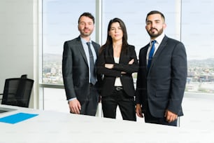 Portrait de trois avocats professionnels en costume établissant un contact visuel. Des hommes d’affaires occupés et une patronne travaillent ensemble pour faire un travail d’équipe collaboratif