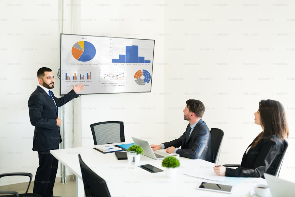 Hispanic boss in a suit giving a talk about a work report to her work professional colleagues at the meeting room