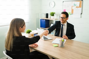Business professional man shaking hands with a female client and colleague after signing a work contract at the corporate office