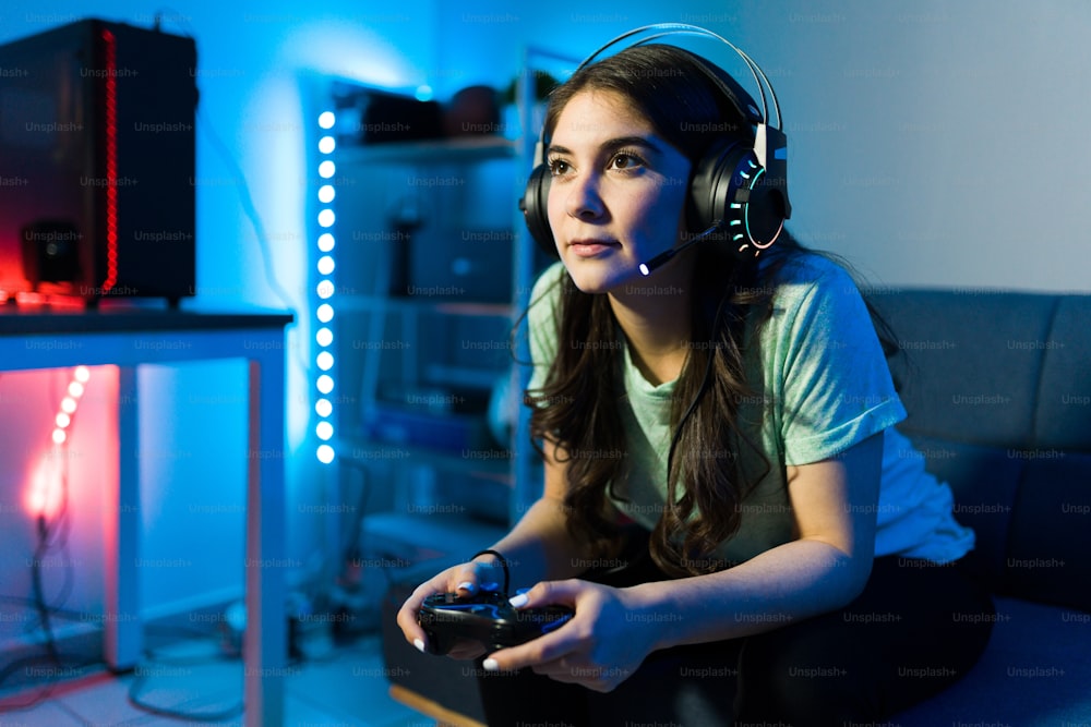 リモコンでビデオゲームに勝つことに焦点を当てた美しい若い女性。寝室で余暇にコンソールでビデオゲームを楽しむ女性ゲーマー