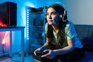 리모콘으로 비디오 게임에서 이기는 데 집중하는 아름다운 젊은 여성. 침실에서 여가 시간을 보내는 동안 콘솔에서 비디오 게임을 즐기는 여성 게이머