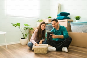 Hispanic couple unpacking boxes and putting things away. Smiling newlyweds looking at a picture frame of their wedding on their new home