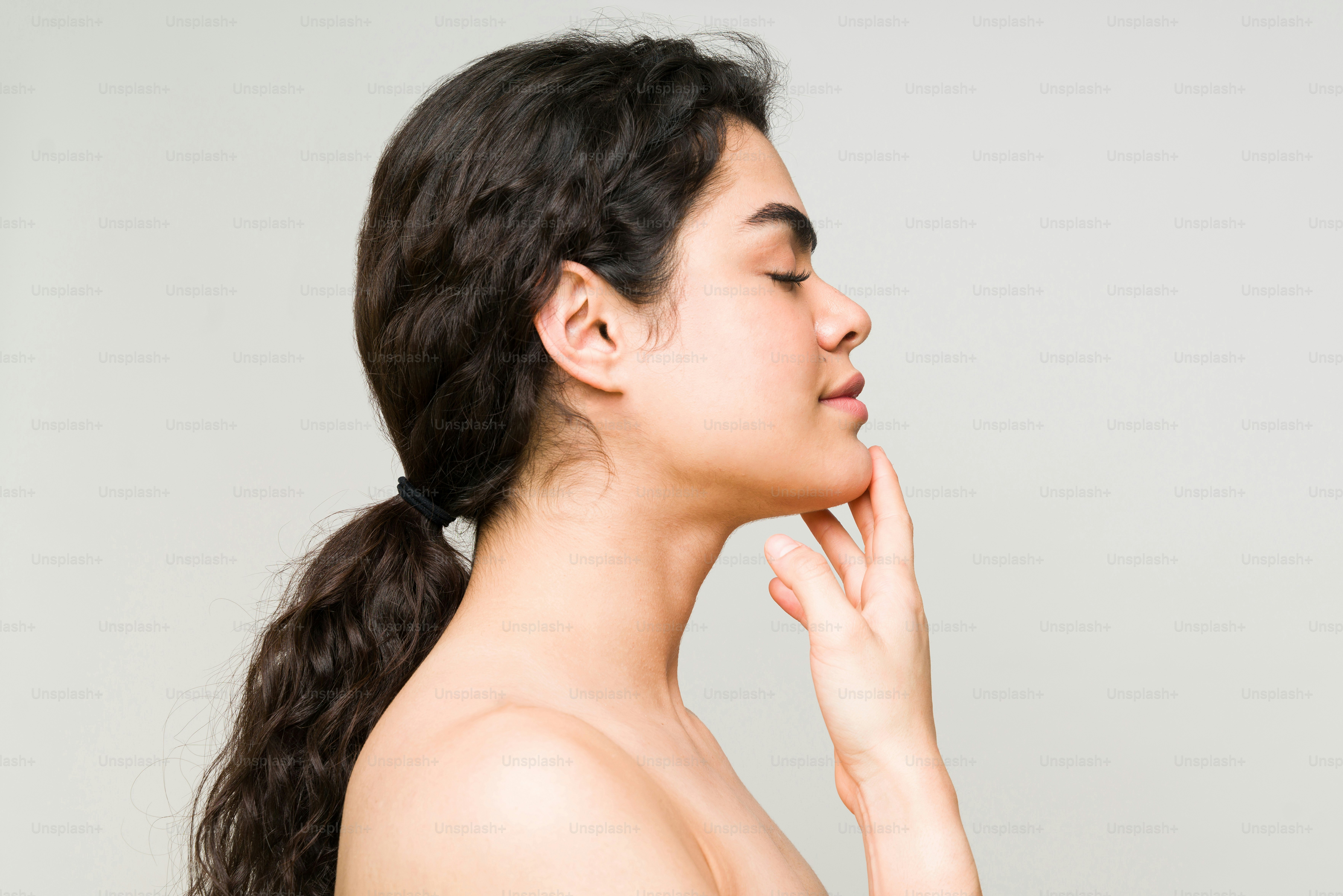 Profil einer hispanischen Frau in ihren 20ern mit geschlossenen Augen, die entspannt aussieht, weil sie eine Gesichtsbehandlung im Beauty-Spa erhalten hat