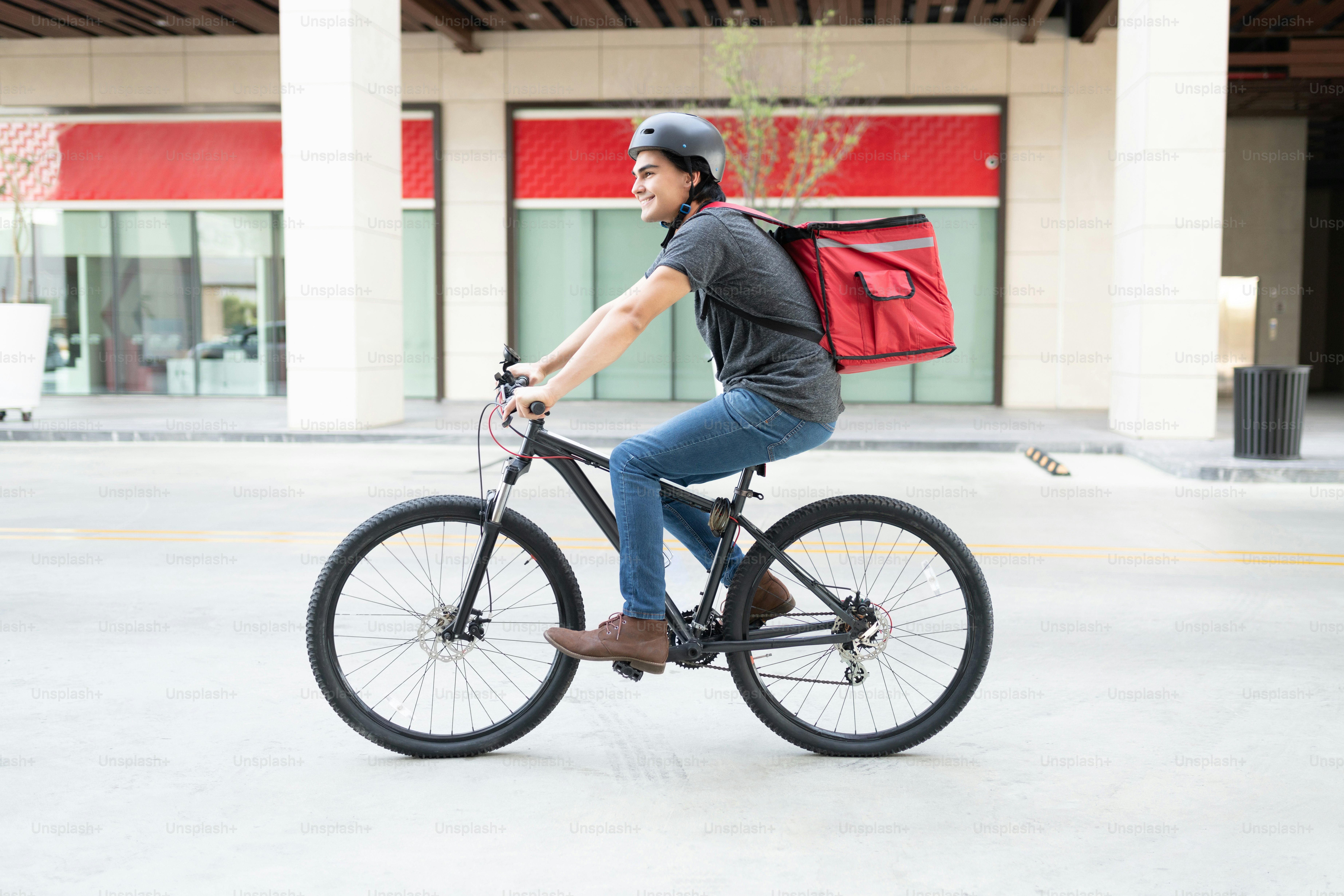 Smiling Hispanic young man out for delivery on bicycle in city