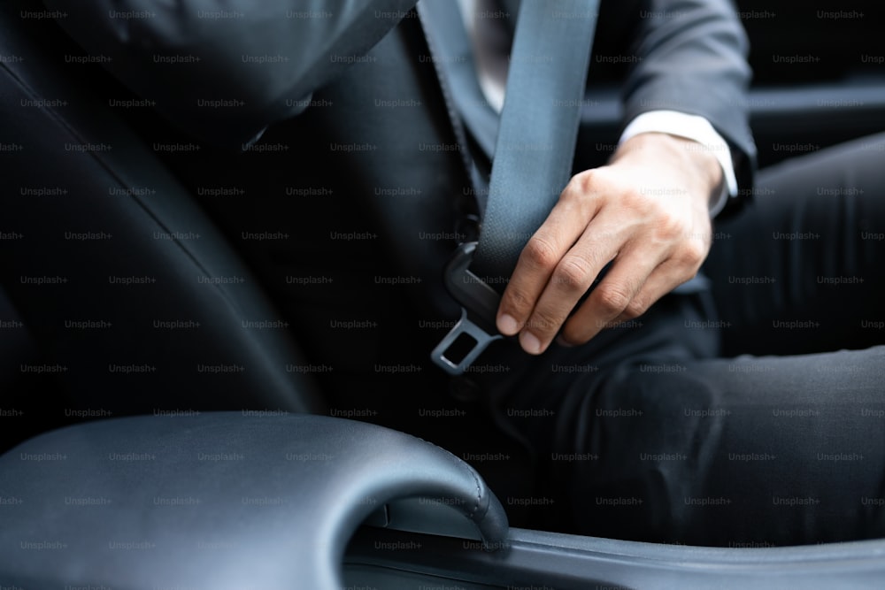 Sezione centrale dell'uomo d'affari che regola la cintura di sicurezza mentre viaggia in auto