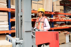 Supervisore donna sicura che utilizza il carrello elevatore tramite rack in fabbrica
