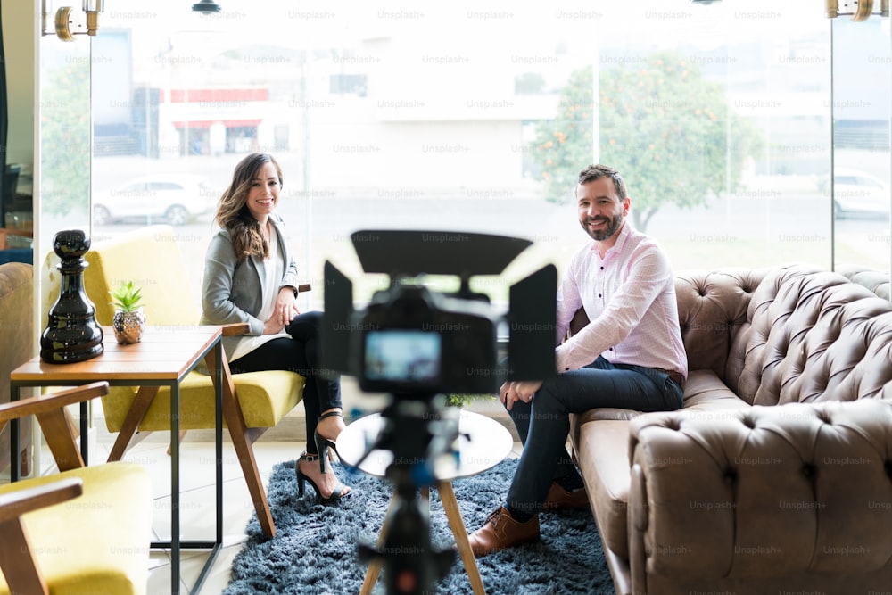 Smiling businessman and journalist looking at video camera during corporate interview in office