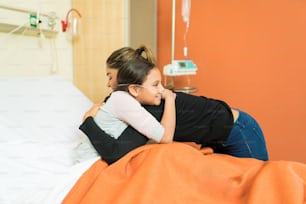 Mutter umarmt Tochter und trifft sie nach der Operation in einem Krankenhauszimmer