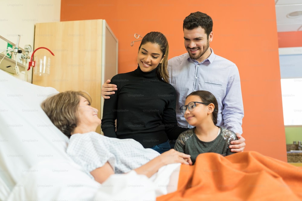Smiling family visiting senior woman during treatment at hospital