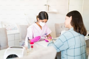 Manicurista latina dando servicios a clienta en spa de uñas