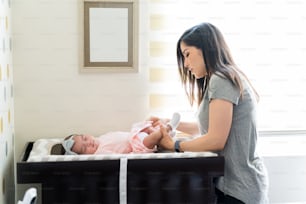 Side view of mother changing baby's diaper at home