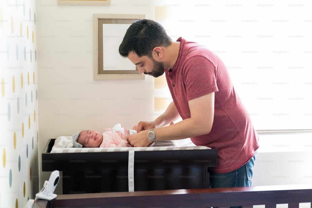 Hispanic father changing newborn daughter's diaper
