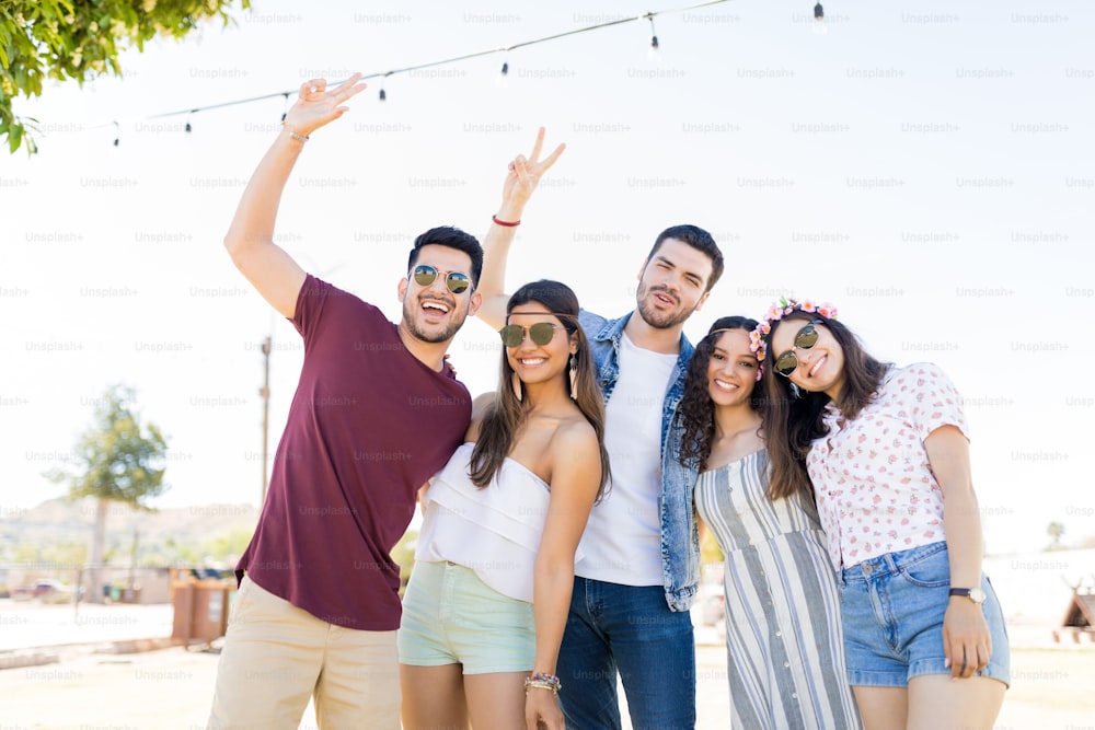 Hispanic women with male friends making victory sign at music festival
