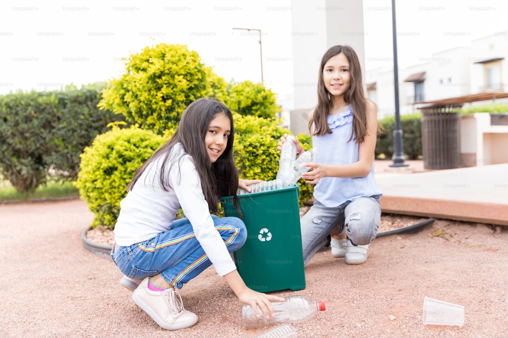 Cute and Hispanic siblings filling garbage into recycle bin on Earth Day