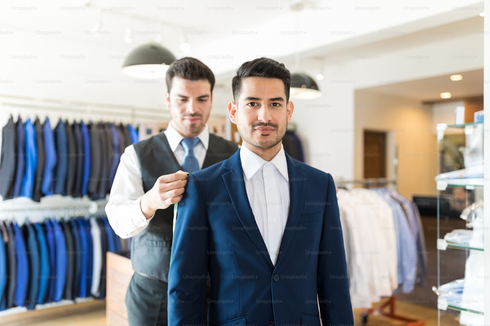 Tailor taking back measurements of good looking client in order to make new suit at shop