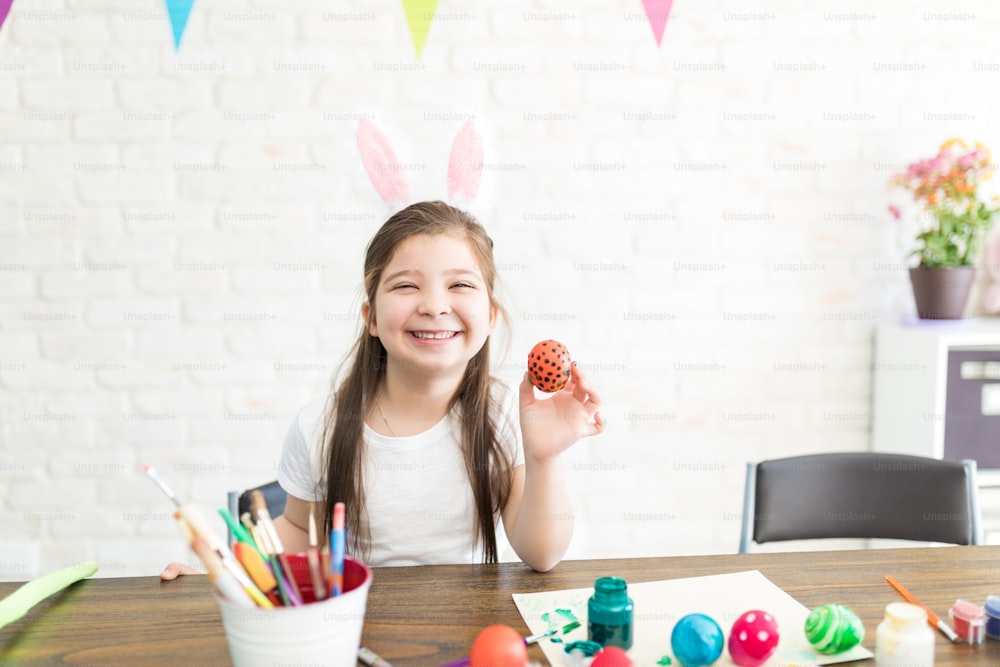 Fille heureuse montrant son œuf de Pâques peint créatif à la maison
