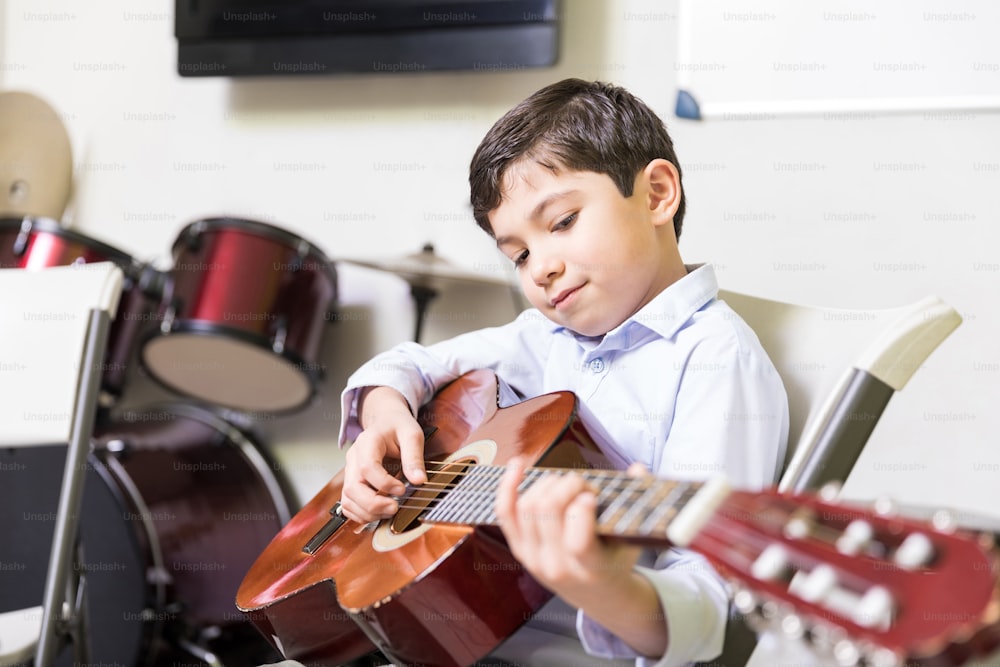 Confident boy improving his speed of playing guitar in music school