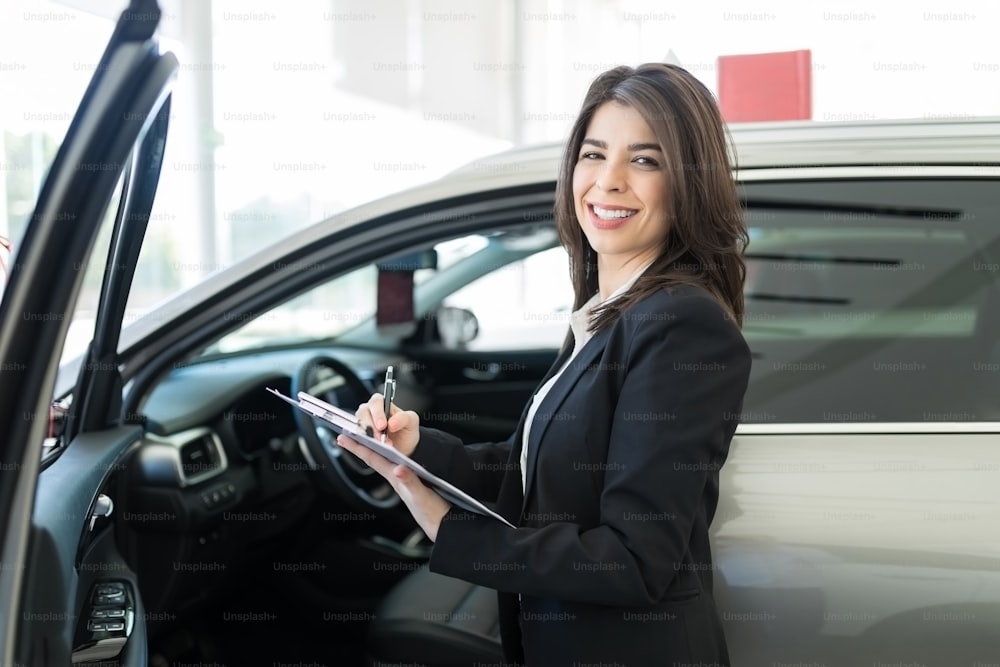 Une vendeuse brune rédige les spécifications de l’intérieur de la voiture au salon