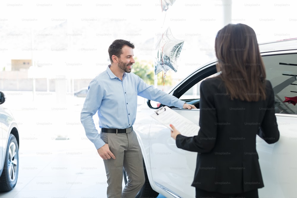 Smiling mid adult customer planning to buy luxury car from dealership