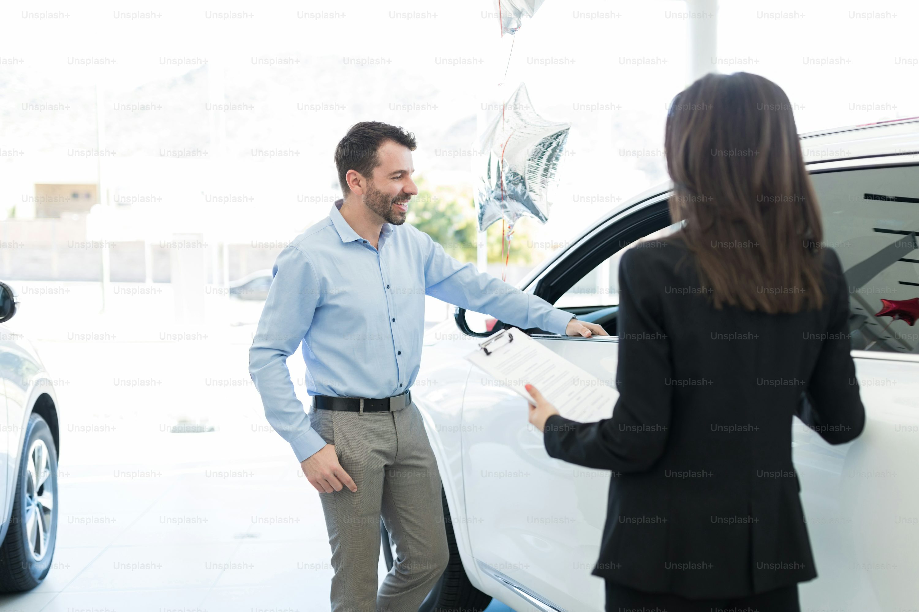 Smiling mid adult customer planning to buy luxury car from dealership