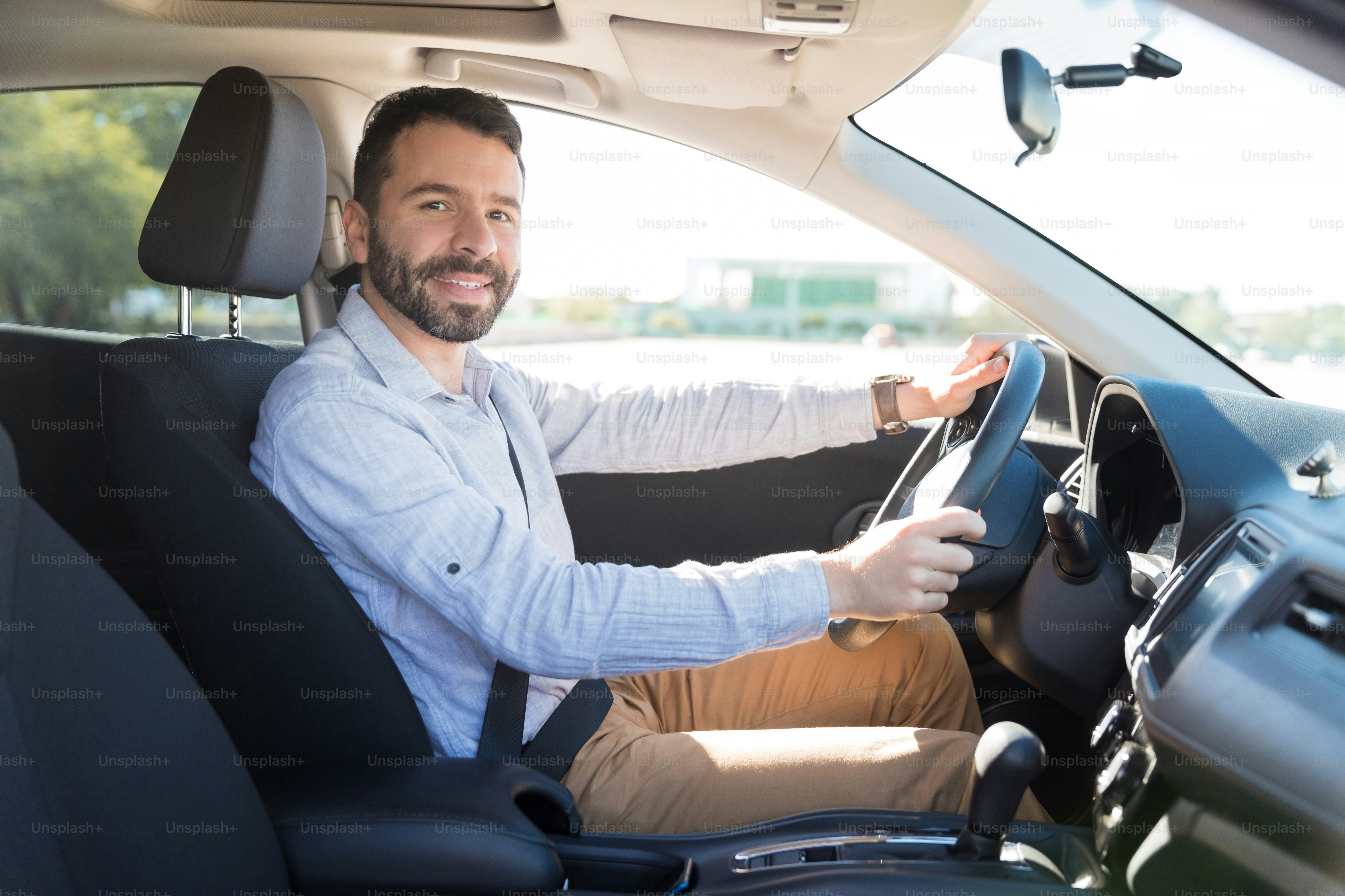 Confident mid adult owner sitting in driving seat of his car and ...