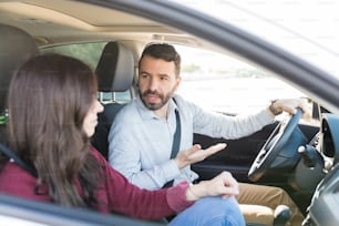 Guapo hombre latino conduciendo mientras pelea con una mujer en el coche