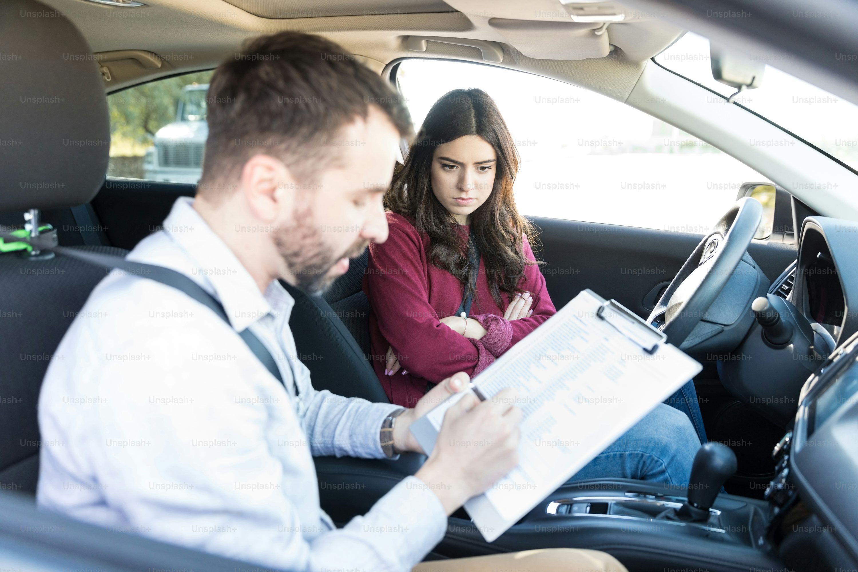 Angry female learner looking at driving coach rejecting license application in car