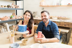 Kreatives Paar, das seine Endprodukte aus dem Radwerfen in der Werkstatt zeigt