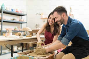 Happy mid adult couple showing their creativity while dating in pottery class