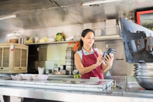 Cute young woman working in a food truck and swiping a credit card to process a payment