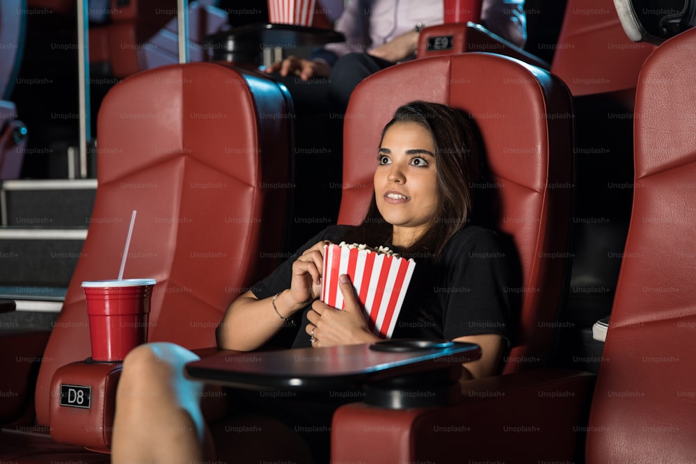 映画館で一人で本当に怖い映画を見ている若い女性