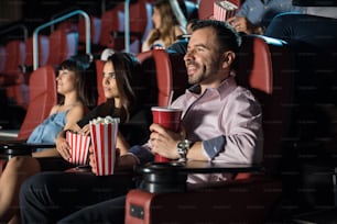 Crowd of good looking people eating snacks and having a good time at the movie theater