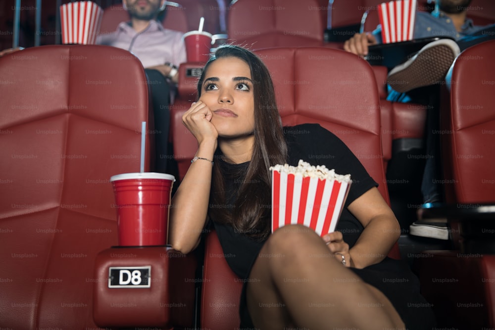 Attractive young brunette looking really bored at the movie theater