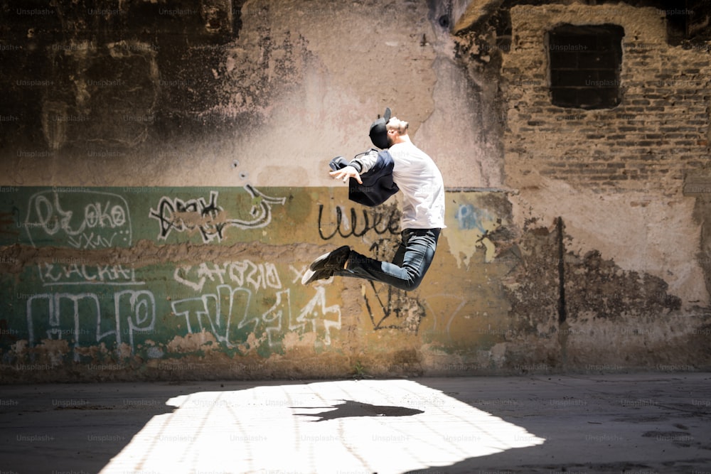 Profilansicht eines männlichen urbanen Tänzers, der einige Tanzbewegungen übt und im Freien springt