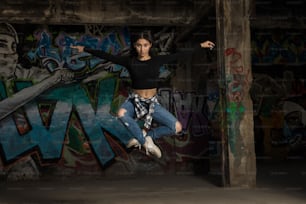 Retrato de uma dançarina bonita pulando e fazendo contato visual na frente de uma parede de grafite