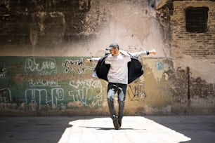 Ritratto a figura intera di un bel ballerino hip hop freestyling all'aperto in un edificio abbandonato