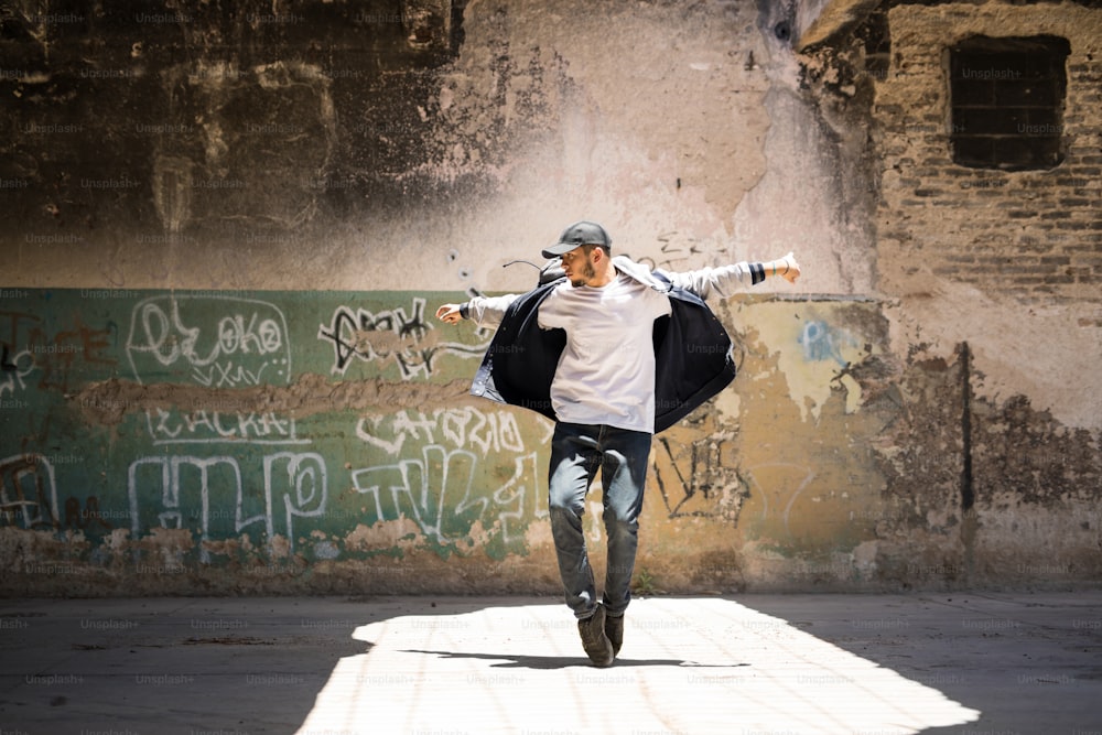 Retrato de corpo inteiro de um belo dançarino de hip hop freestyling ao ar livre em um edifício abandonado