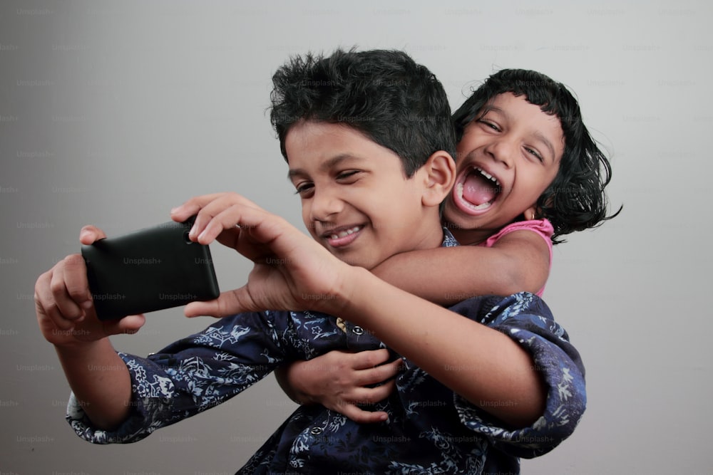 Junge und Mädchen haben Spaß beim Selfie mit einem Handy