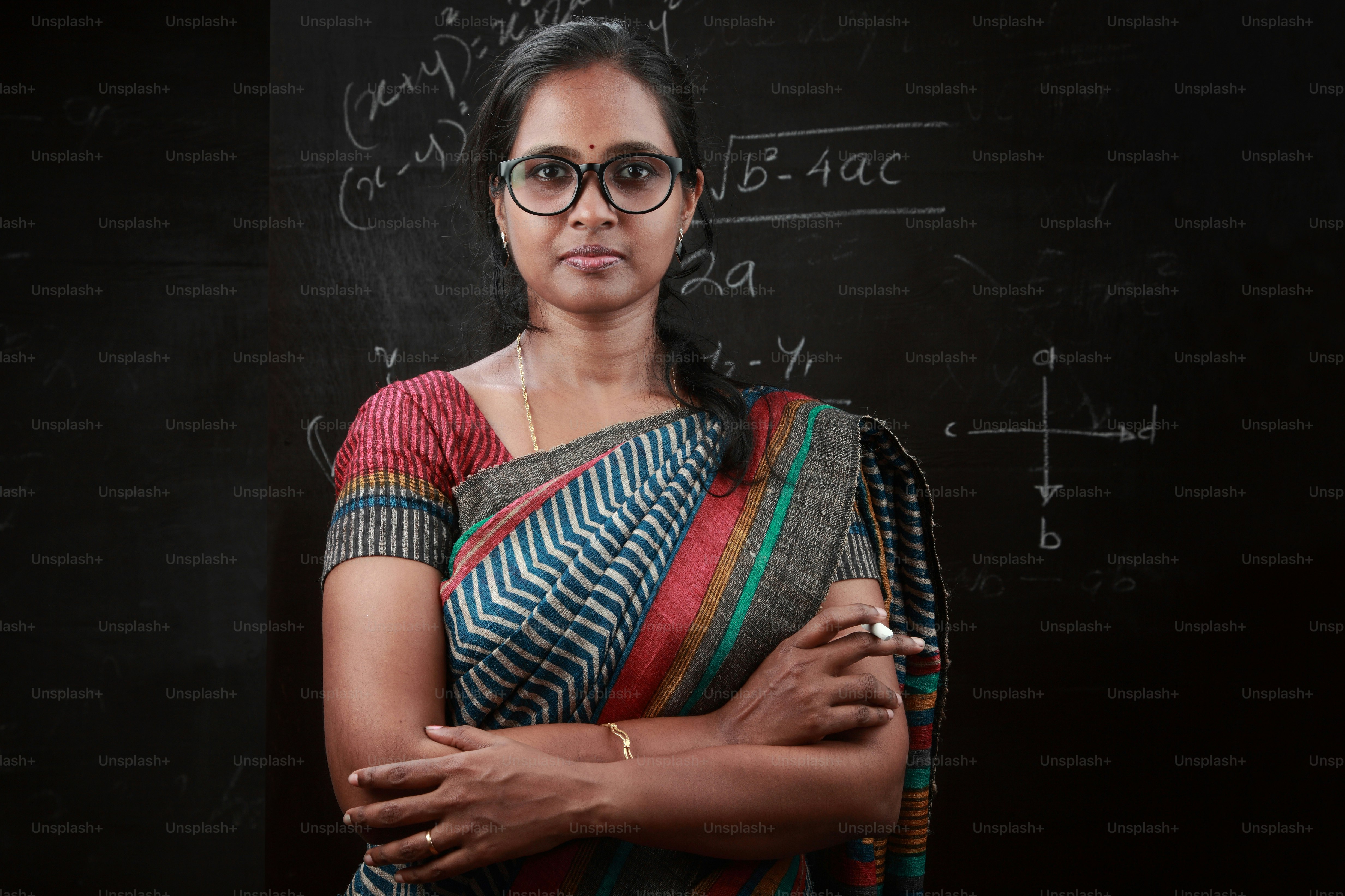Portrait of an Indian lady teacher stands in front of a blackboard