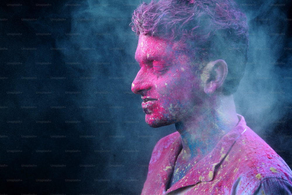 Young man smeared with colours plays Holi.Concept for Indian festival Holi.