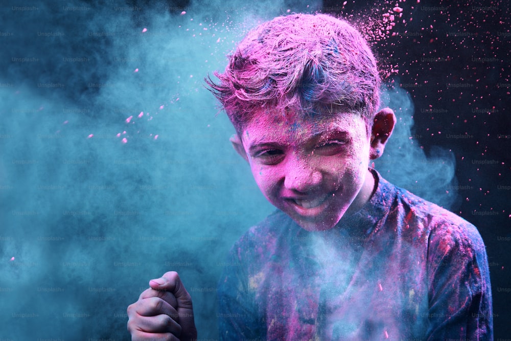 어린 소년은 색을 가지고 논다. 인도 축제 홀리의 개념