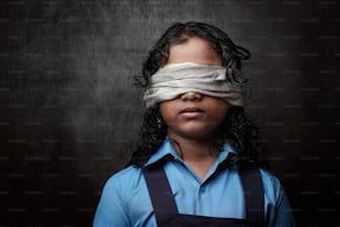 Light and shade portrait of a blindfolded school girl in a dark background